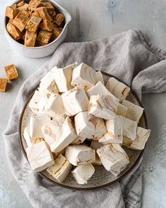 tofu cubes are on a plate next to a bowl of tofu chunks