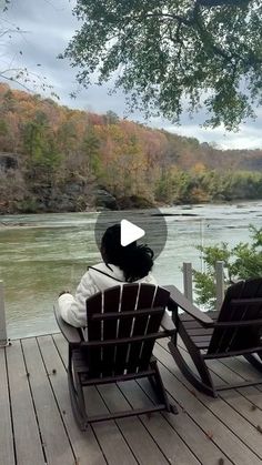 two chairs sitting on a wooden deck next to a river