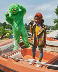 a person in a costume standing on a boat with a green monster behind them and holding a cell phone to their ear