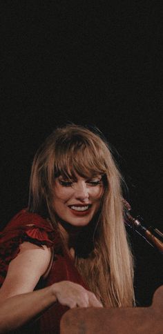 a woman with long blonde hair wearing a red dress and holding a wooden instrument in her hand