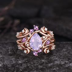 a ring with an amethorate stone surrounded by pink and white diamonds on a rock