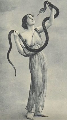 an old photo of a woman holding a snake in her hand and looking up at the sky