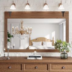 a bedroom with a large mirror, dresser and chandelier on the wall above it