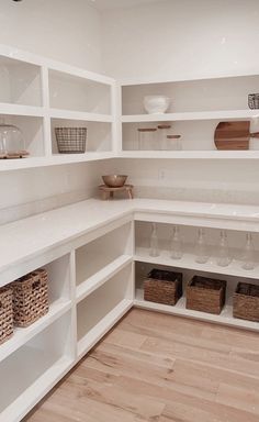 an empty pantry with white shelves and baskets