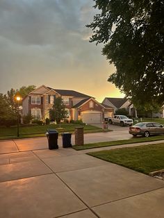 two trash cans sitting on the sidewalk in front of a row of houses at sunset