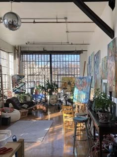 an artist's studio with large windows and paintings on the wall