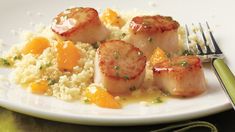 seared scallops with apricots and rice on a plate next to a fork