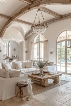 a living room filled with furniture and a chandelier hanging over it's windows