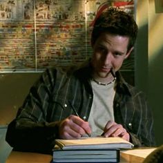 a man sitting at a desk writing on a book