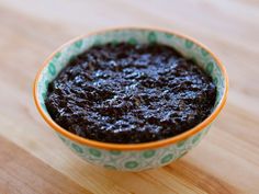 a small bowl filled with black pudding on top of a wooden table