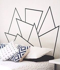 a white bed with black lines on the headboard and pillows in front of it