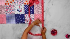 a woman is making a quilt on the wall next to some scissors and other crafting supplies