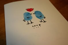 two blue birds are kissing each other on a white card with the word love written in it