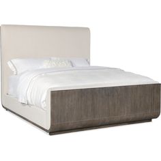 an upholstered bed with white sheets and pillows