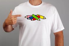 a man is pointing to some crayons on his t - shirt