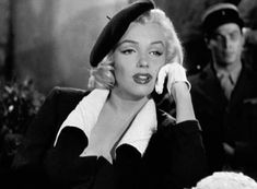 marilyn monroe talking on the phone while standing next to a man