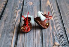 two baby shoes with red and white fur lined up on a wooden floor next to each other