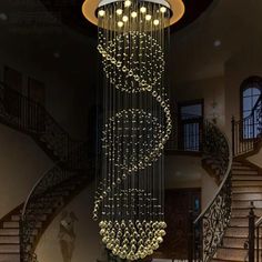 a chandelier hanging from the ceiling in a living room with stairs and railings