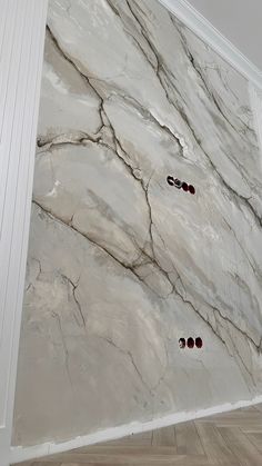 two pairs of shoes sitting on the floor in front of a marble wall with white trim