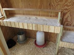 an empty shelf in the corner of a chicken coop with a bucket and sill