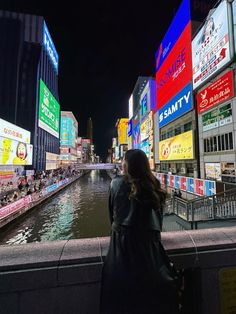 a woman standing on the edge of a bridge looking at billboards