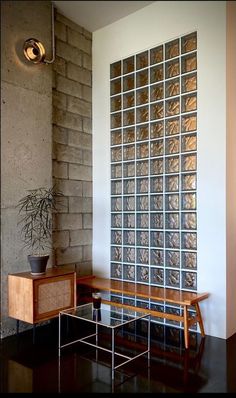 a wooden bench sitting in front of a wall with glass blocks on it's sides