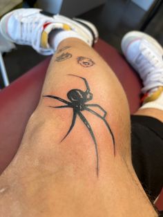 a person with a spider tattoo on their leg sitting in front of a red chair