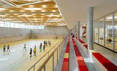 an indoor ice rink with many people on it and red and yellow striped stairs leading up to the ceiling