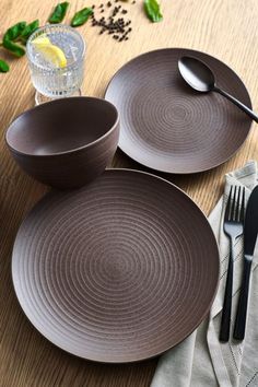 two brown plates sitting on top of a wooden table next to silverware and utensils