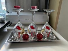 three wine glasses with red and white ornaments on a silver tray