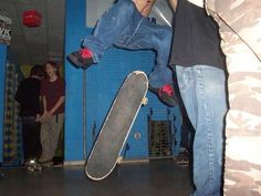 a man doing a trick on a skateboard in front of other people standing around