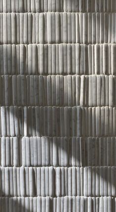 the shadow of a person standing in front of a wall made out of strips of paper