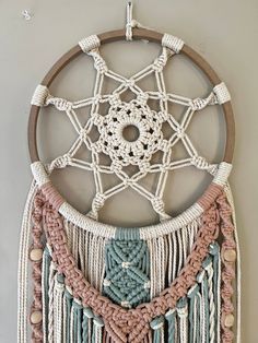 a wall hanging made with macrame and yarns in the shape of a dream catcher