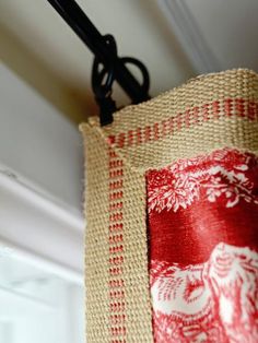 a pair of scissors hanging from the side of a window sill next to a red and white curtain