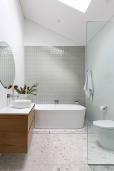 a bathroom with a toilet, sink and bathtub next to a shower stall under a skylight