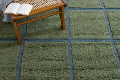 a chair with a book on it sitting in front of a rug that looks like squares