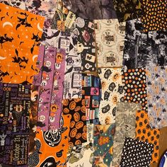 an assortment of halloween themed items are arranged on a table cloth covered with various patterns and colors