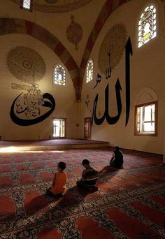 two children are sitting on the floor in front of an ornate wall with arabic writing