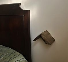 a wooden birdhouse on the wall next to a bed