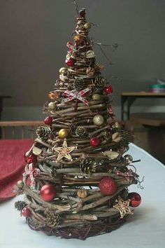 a small christmas tree made out of branches and twigs with ornaments on top, sitting on a table