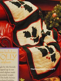 a crocheted christmas blanket with holly leaves on it is sitting in a chair