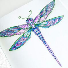 a drawing of a dragonfly sitting on top of a piece of paper with intricate designs