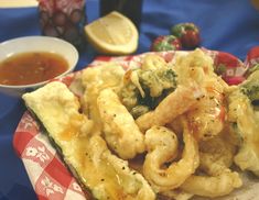 a plate full of fried food next to a bowl of dipping sauce