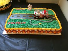 a birthday cake that is shaped like a firetruck and has grass on it