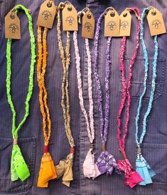 several different colored hair ties are hanging on a coat jacket with tags attached to them