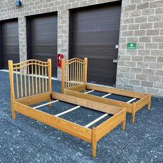 two wooden beds sitting next to each other in front of a brick building with garage doors