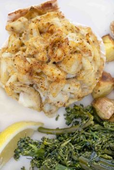 some broccoli and cauliflower on a white plate with lemon wedges