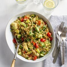 a bowl filled with rice and vegetables next to silverware on top of a table