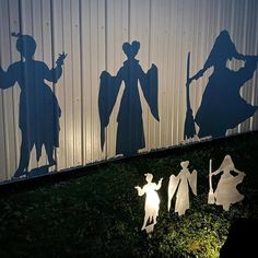 the silhouettes of three people are shown in front of a corrugated wall and grass