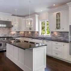 a large kitchen with white cabinets and black counter tops, along with an island in the middle